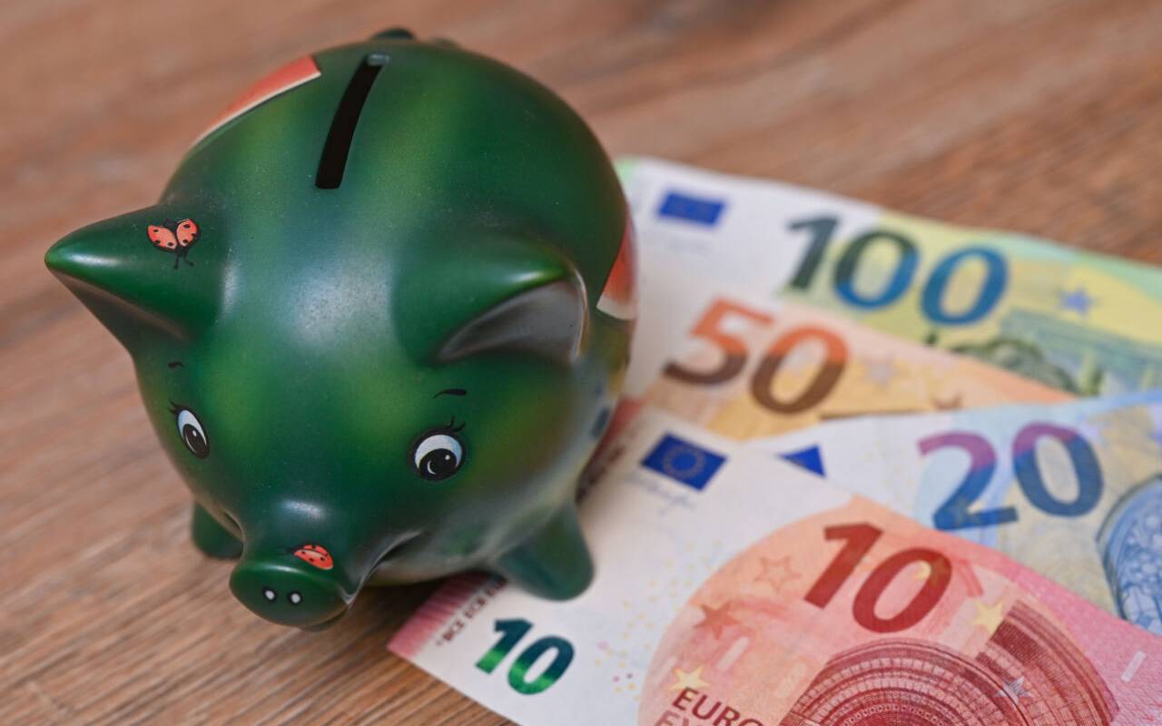 Eine Spardose mit Geldscheinen liegt auf einem Tisch