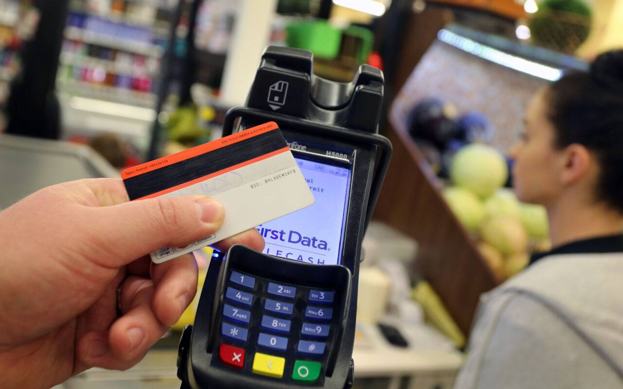 Eine Karte wird an den Bezahl-Terminal an der Kasse eines Supermarktes gehalten