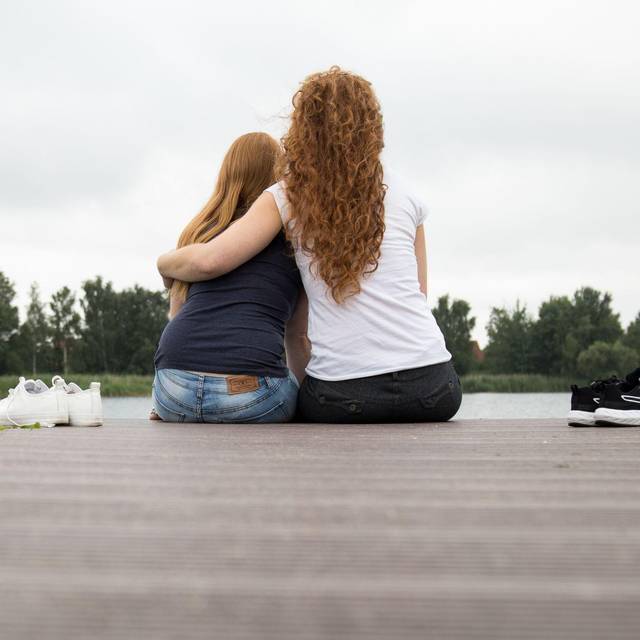 Zwei Frauen sitzen auf einem Steg am See