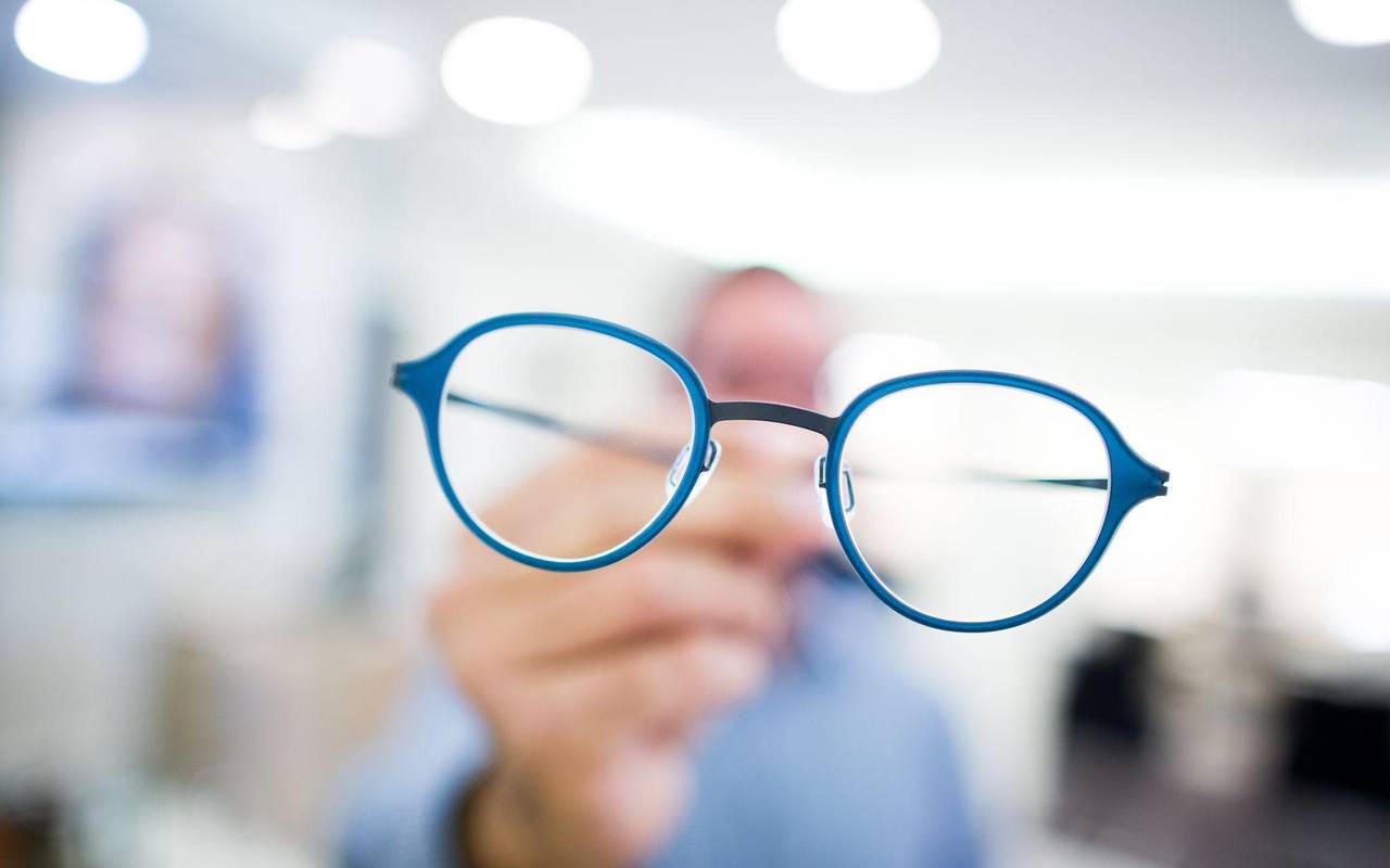 Optiker hält eine Brille in der Hand