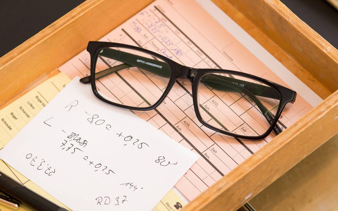 Zettel mit den Messwerten der Sehstärke liegt neben einer Brille
