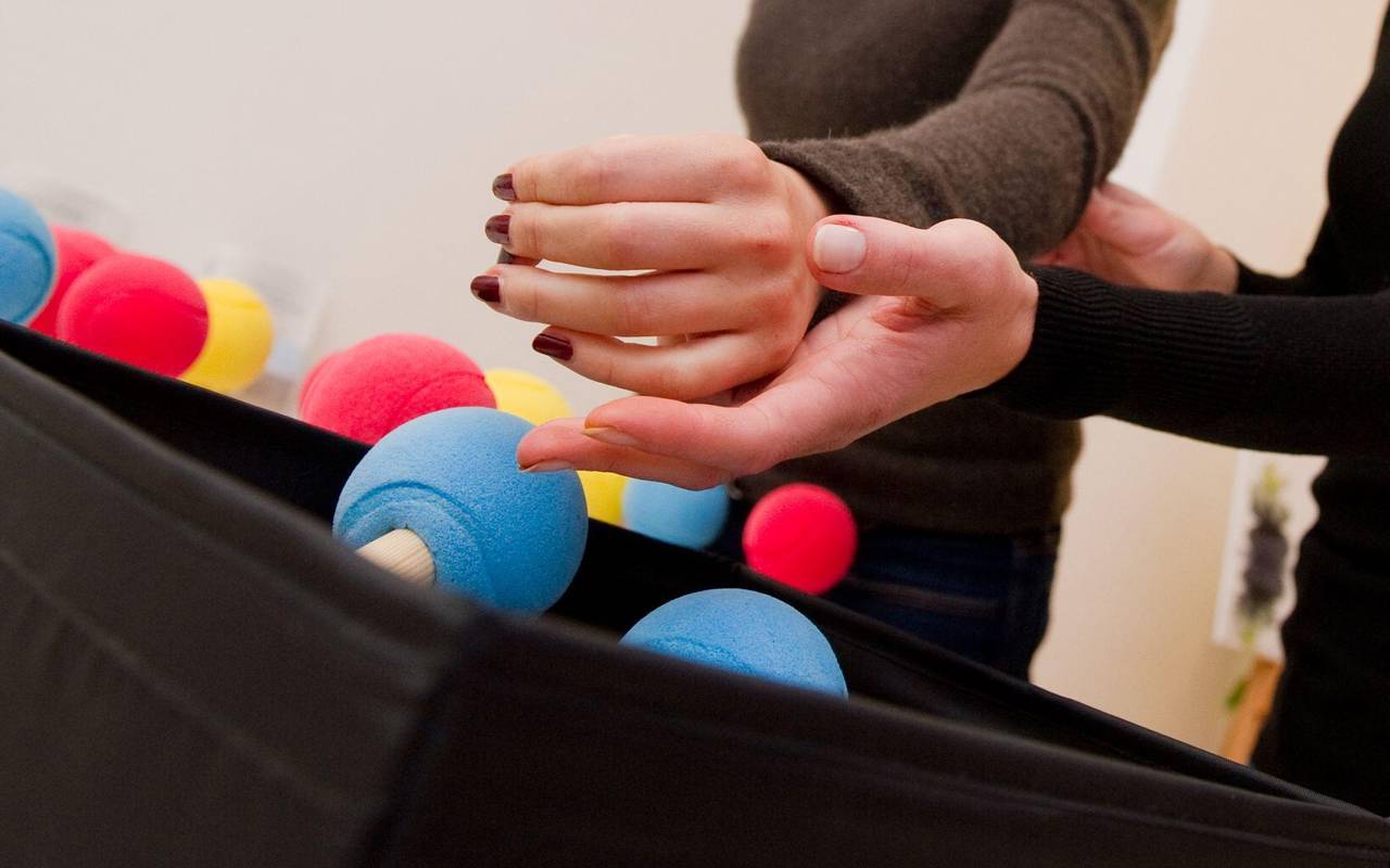 Eine Ergotherapeutin trainiert die Hand einer Patientin