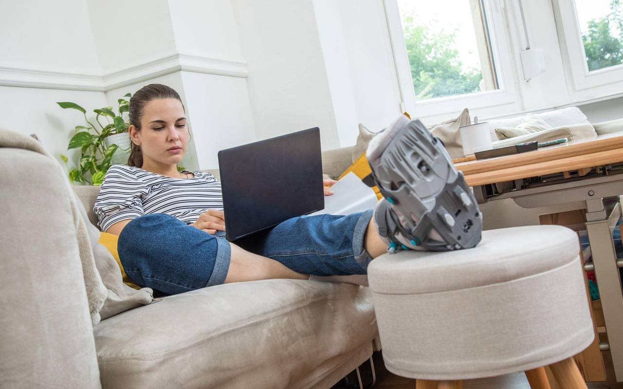 Eine Frau mit Fuß im Gips auf dem Sofa