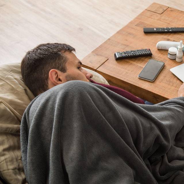 Ein Mann mit Erkltung bedient ein Laptop