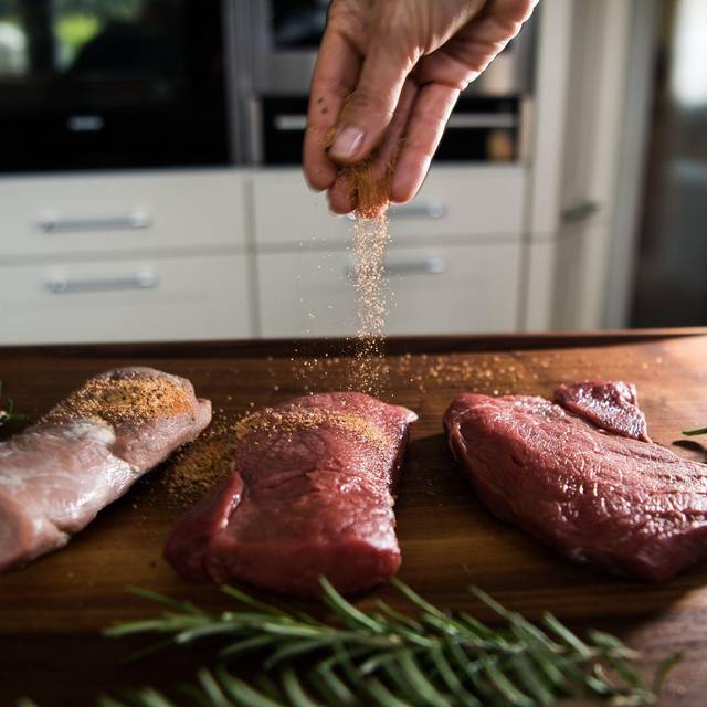 Eine Perosn würzt Fleisch