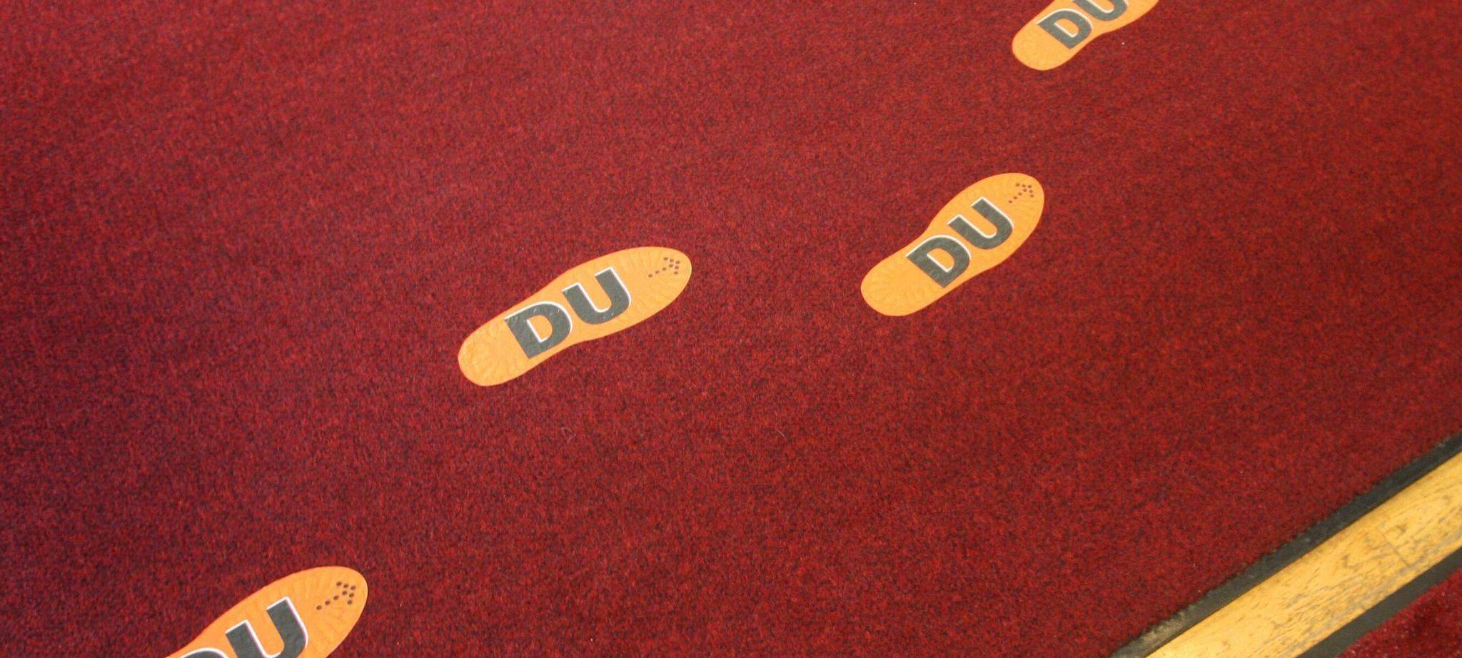 Aufgeklebte Fußstapfen mit der Aufschrift "DU"