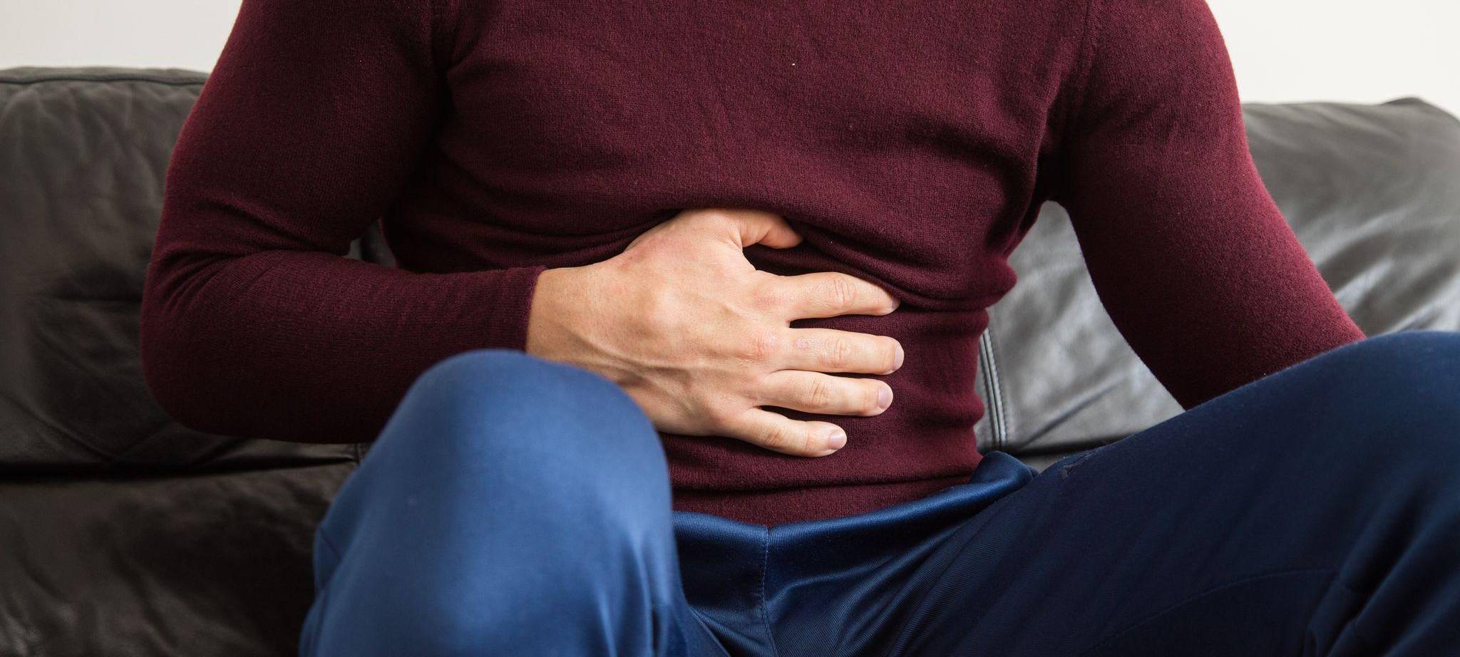 Ein Mann fasst sich mit der Hand an den Bauch