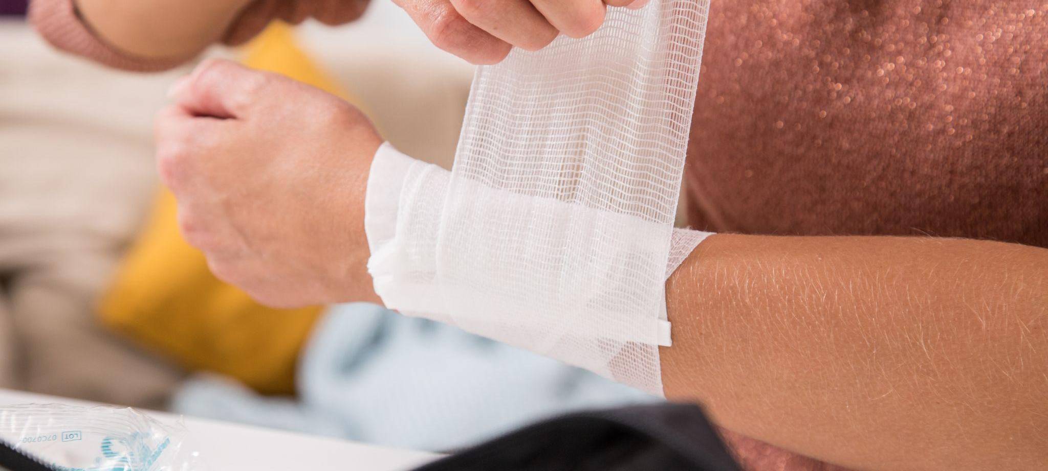 Frau verbindet eine Wunde mit Verbandsmaterial