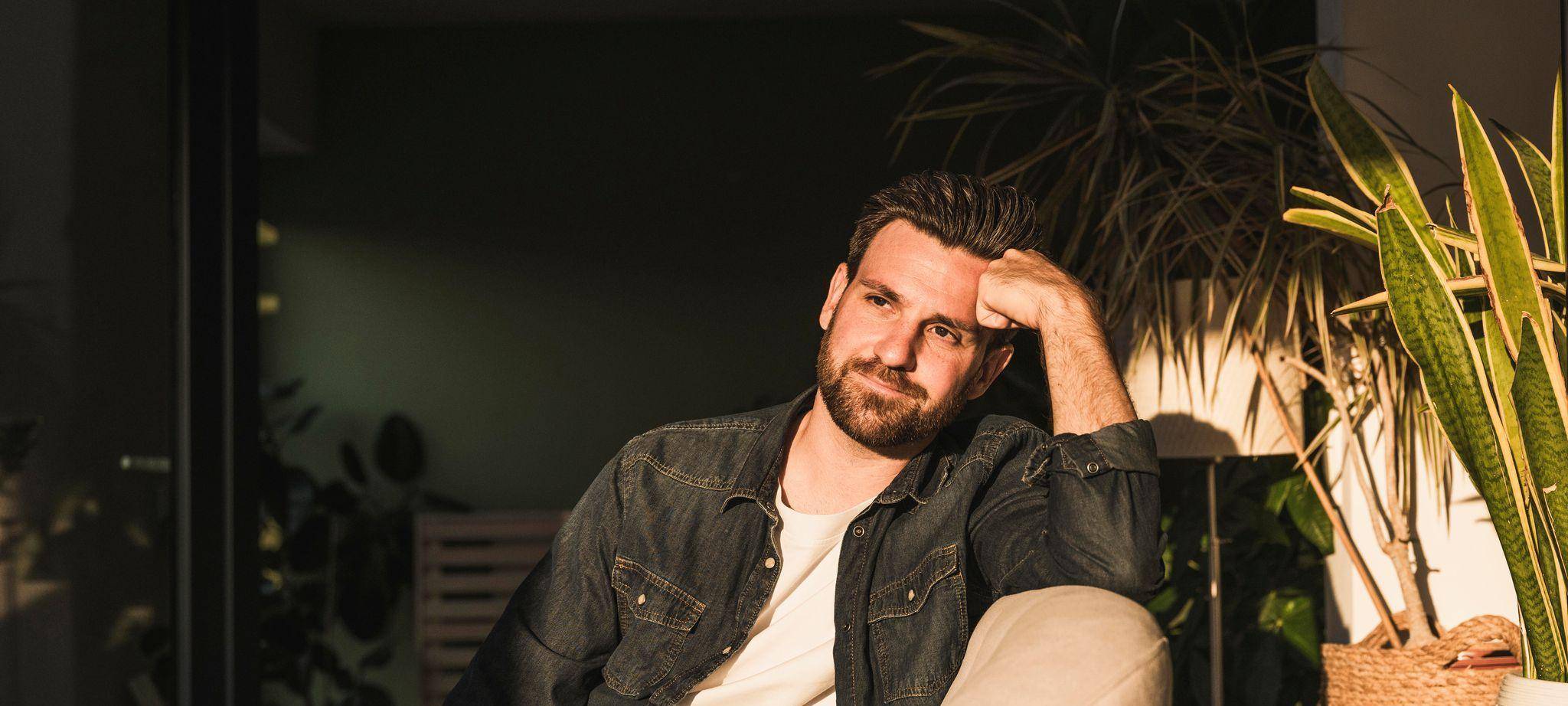 Mann sitzt gedankenvoll auf einer Couch