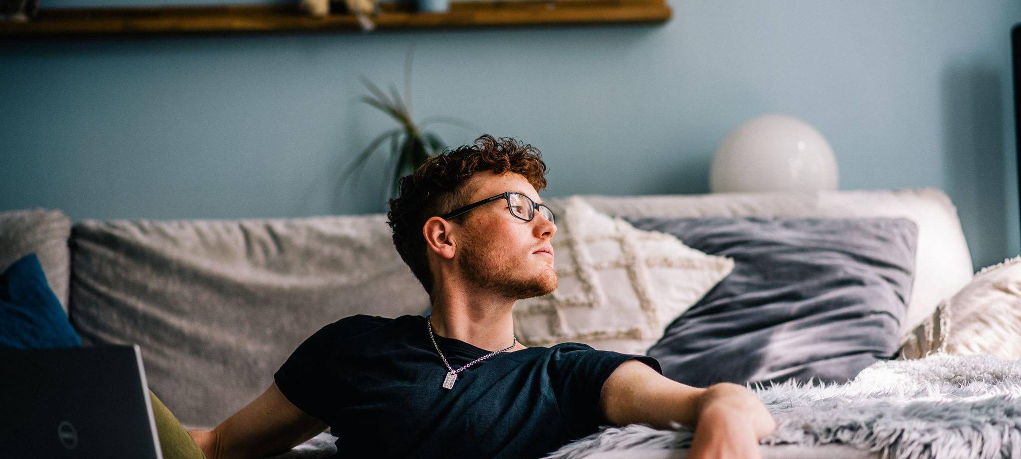 Ein junger Mann sitzt auf dem Boden vor seinem Computer