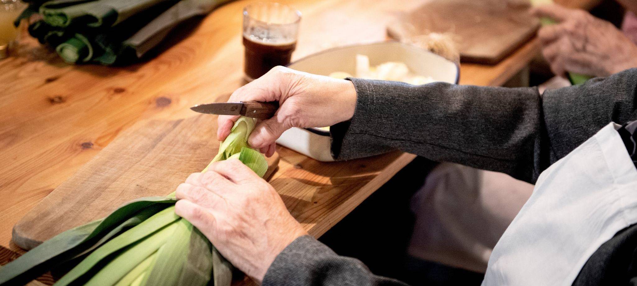 Eine Seniorin schneidet Lauch klein