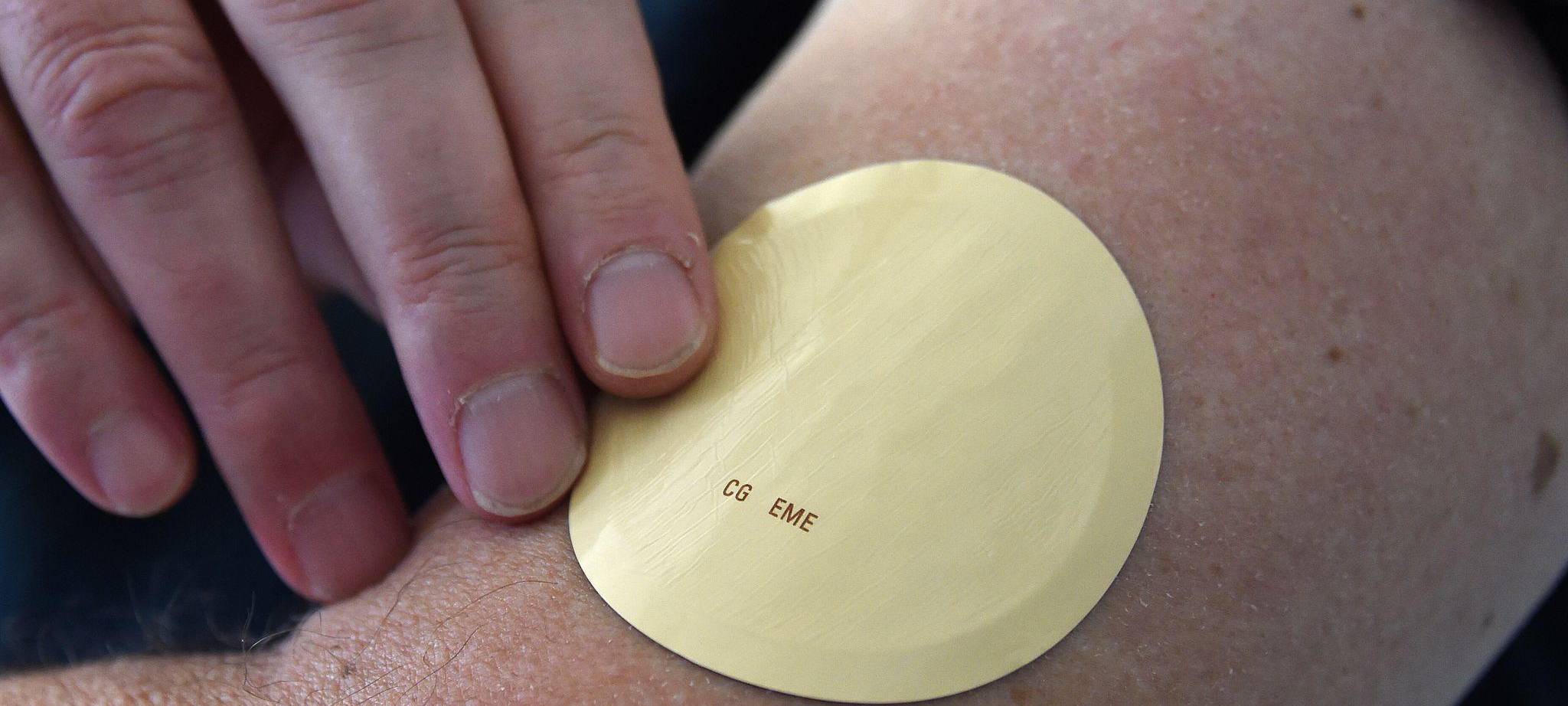 Eine Person trägt ein Wirkstoffpflaster am Oberarm