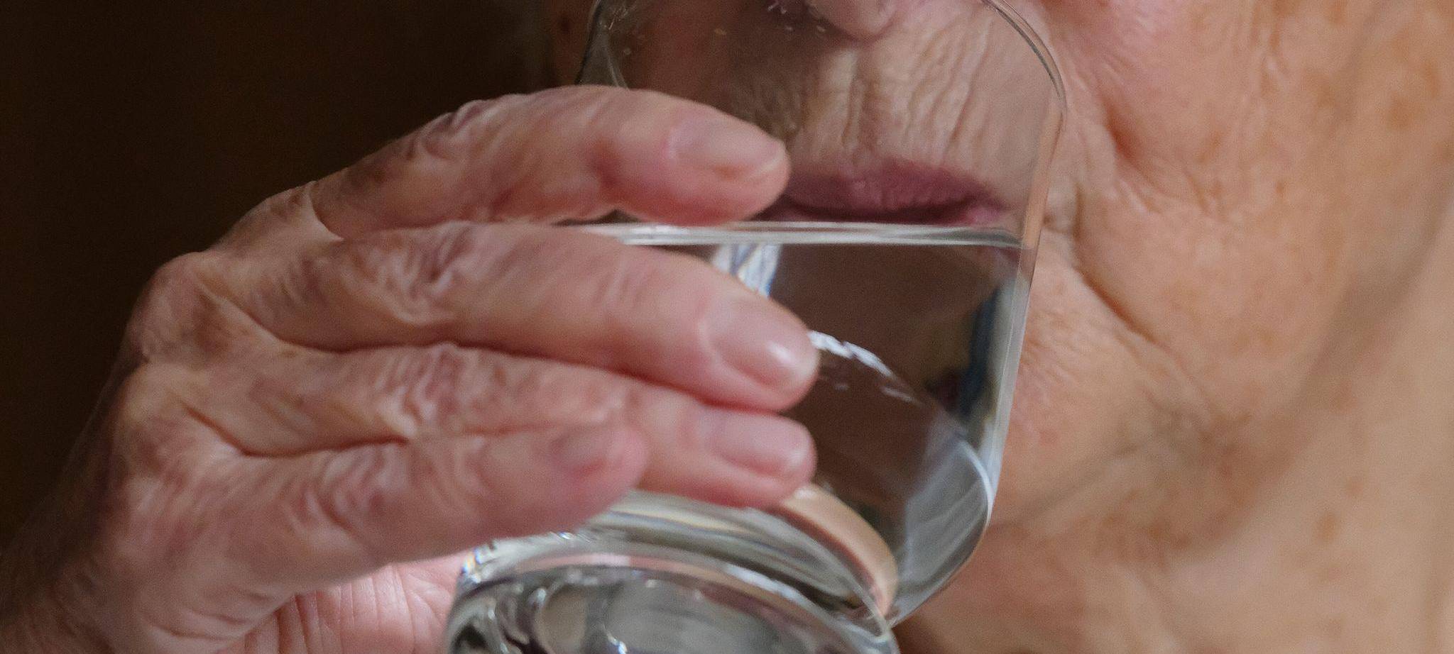 Ältere Frau trinkt ein Glas Wasser